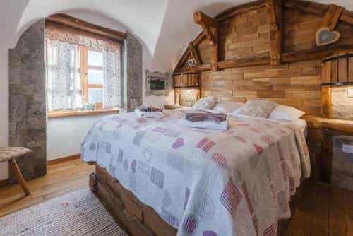 Bedroom with rustic wood paneling, stone accents, and a large bed with a patterned quilt.