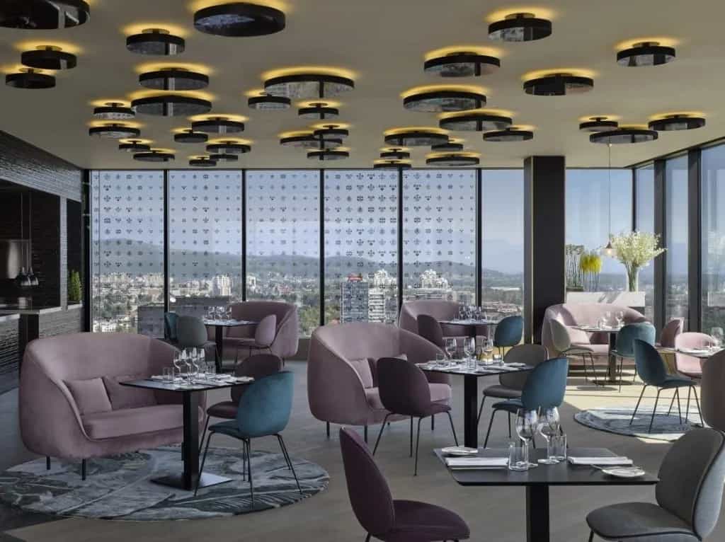 Restaurant dining area with plush seating, modern lighting, and city views from large windows
