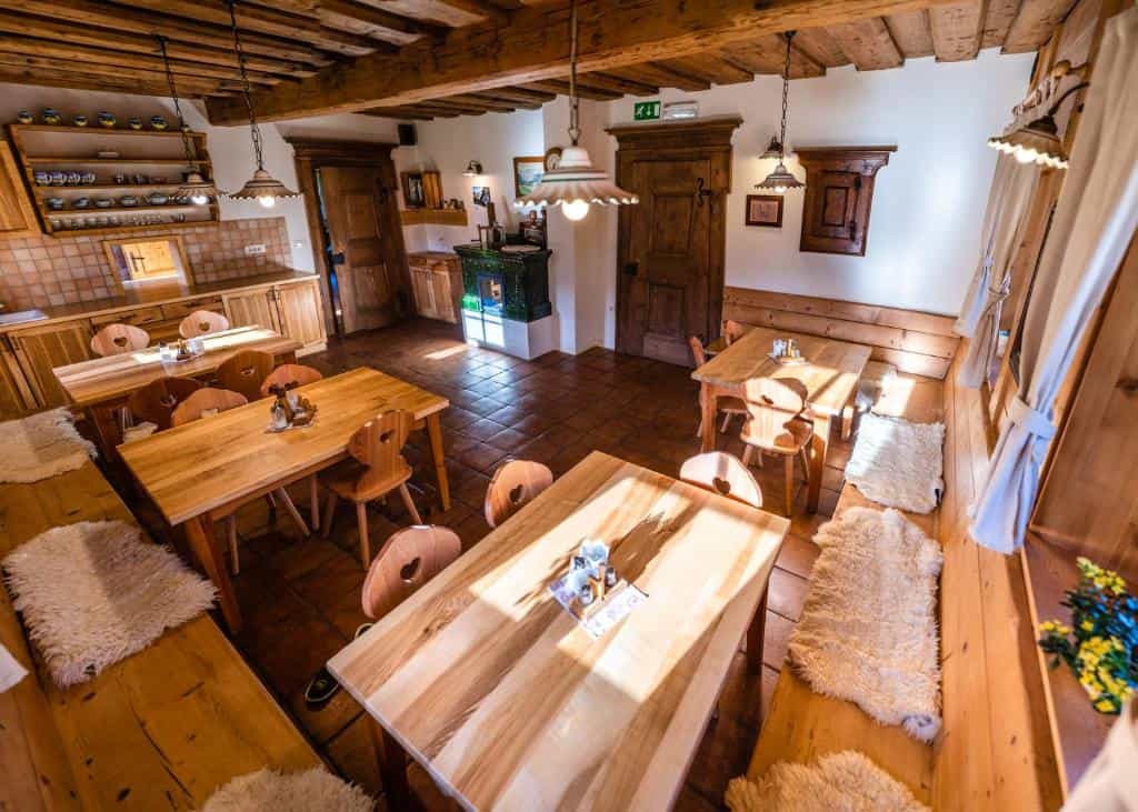 Rustic dining room with wooden tables, chairs with heart cutouts, and sheepskin rugs.