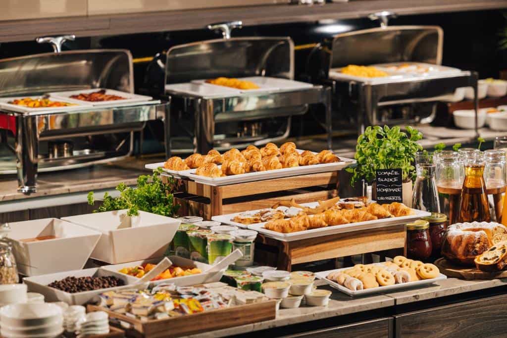Hotel breakfast buffet with croissants, hot chafing dishes, fruit, and baked goods.