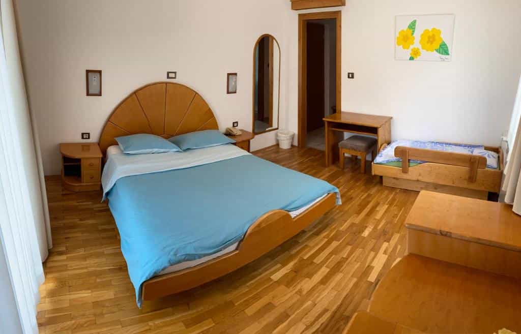 Bedroom with large wooden bed, small cot, and wood floors, likely at Kmetija Hudicevec.
