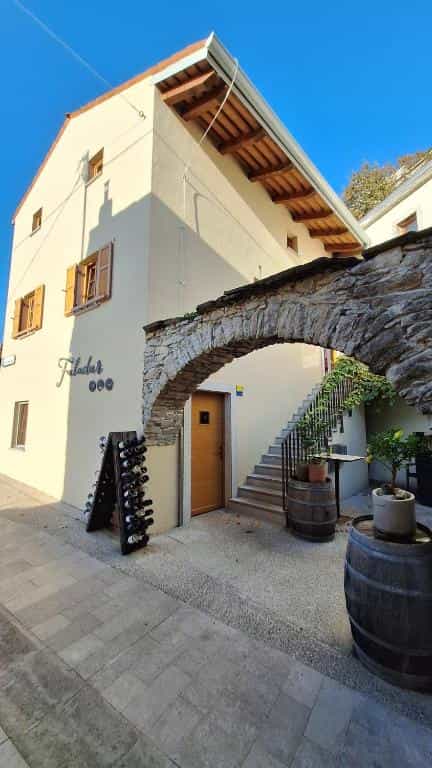 Building entrance with stone archway, wine rack, and barrels in Vipava.
