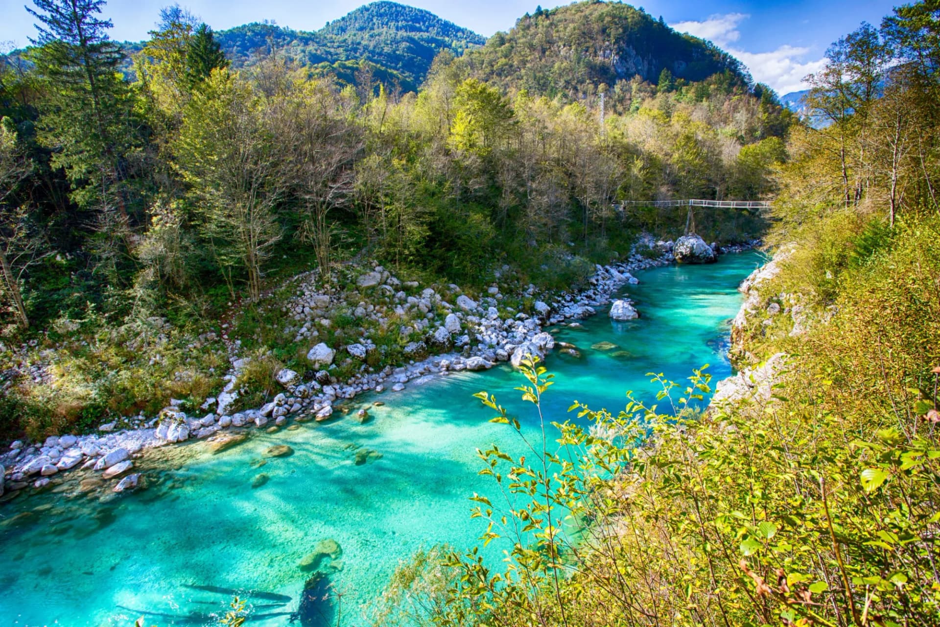 Turquoise Soca River flowing through a rocky gorge surrounded by lush green mountains in Slovenia.