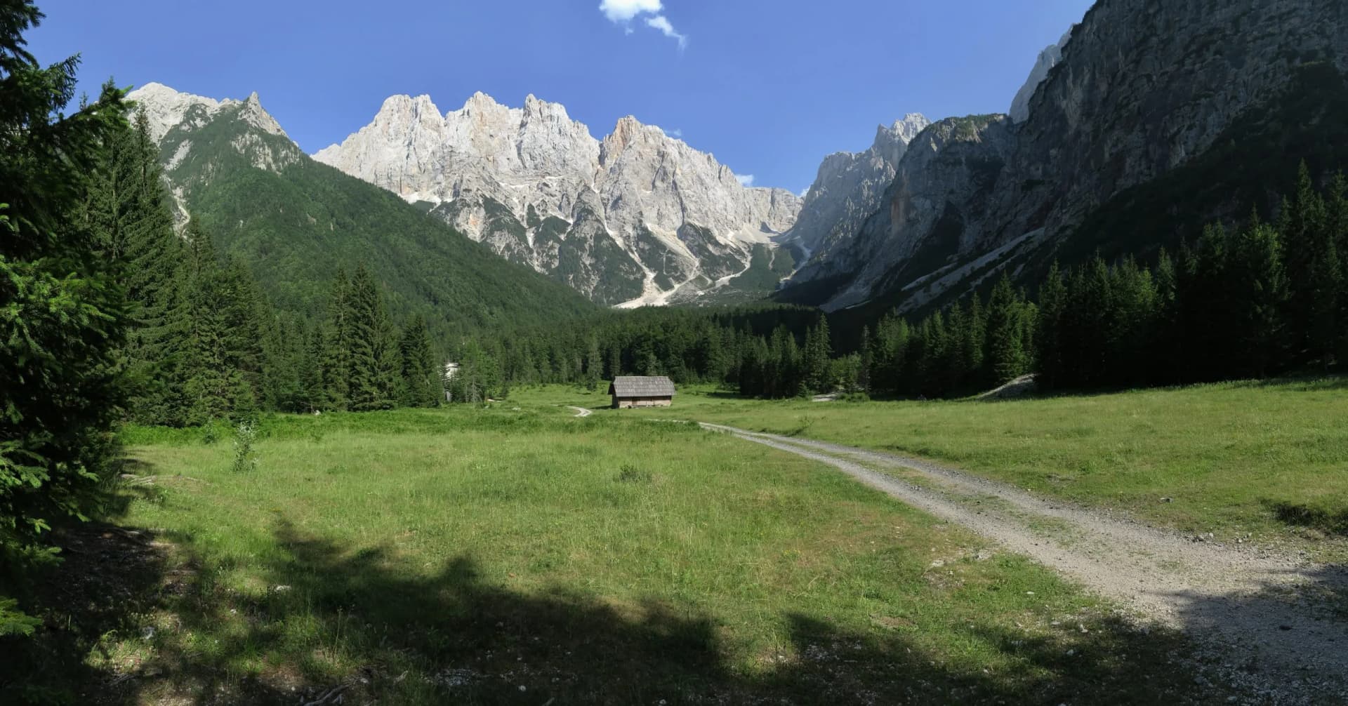 Krnica Valley with the top of Mount Kríž, green meadow, and wooden hut.