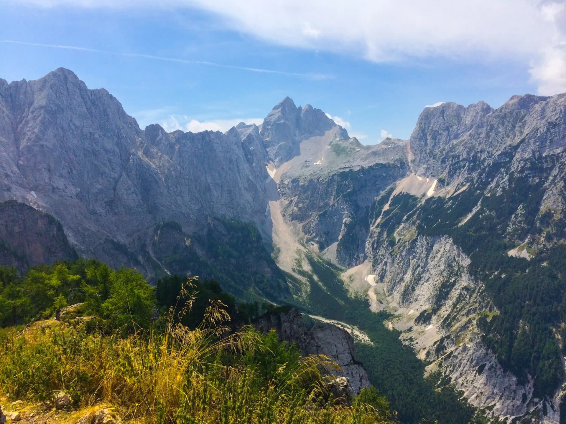 Rugged mountains and steep valley with green forest under a blue sky, view from Slemenova Spica.
