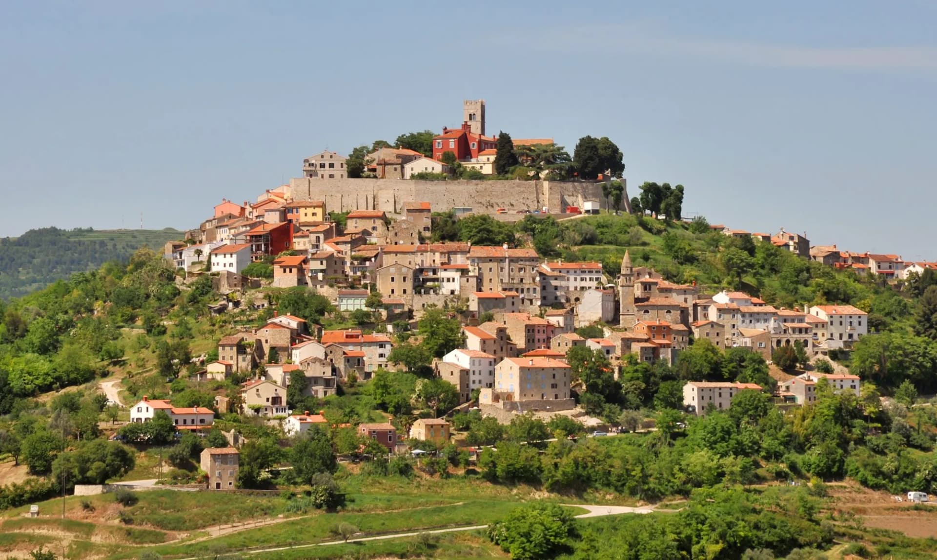 Hilltop town of Motovun with stone buildings and terracotta roofs nestled in lush green hills.