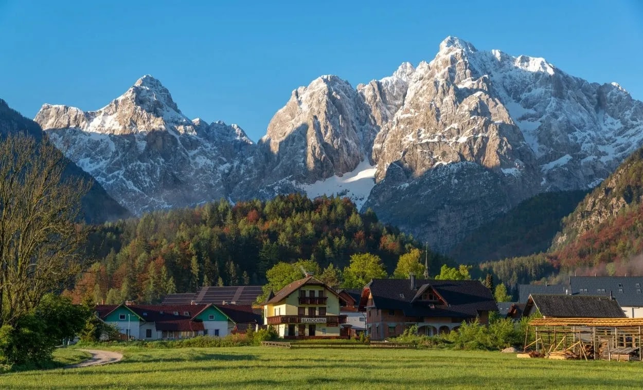 Kranjska Gora village at sunrise with snow-capped Julian Alps mountains in background.