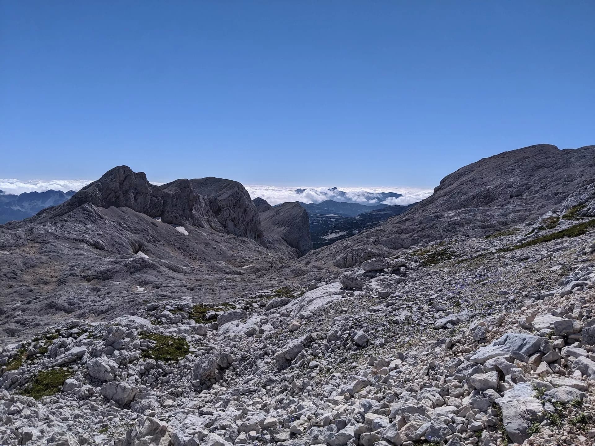 Rocky mountain landscape with peaks above clouds under a clear blue sky