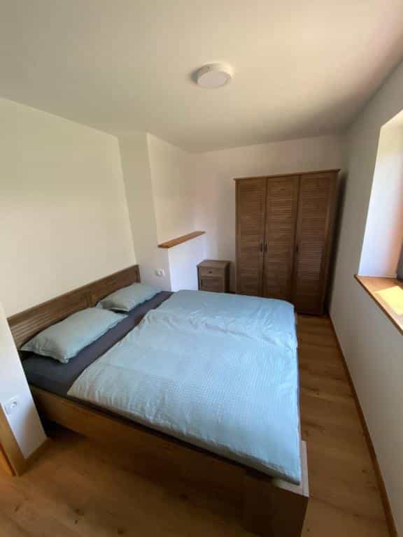 Bedroom with wooden bed, light blue duvet, wardrobe, and wooden floor.