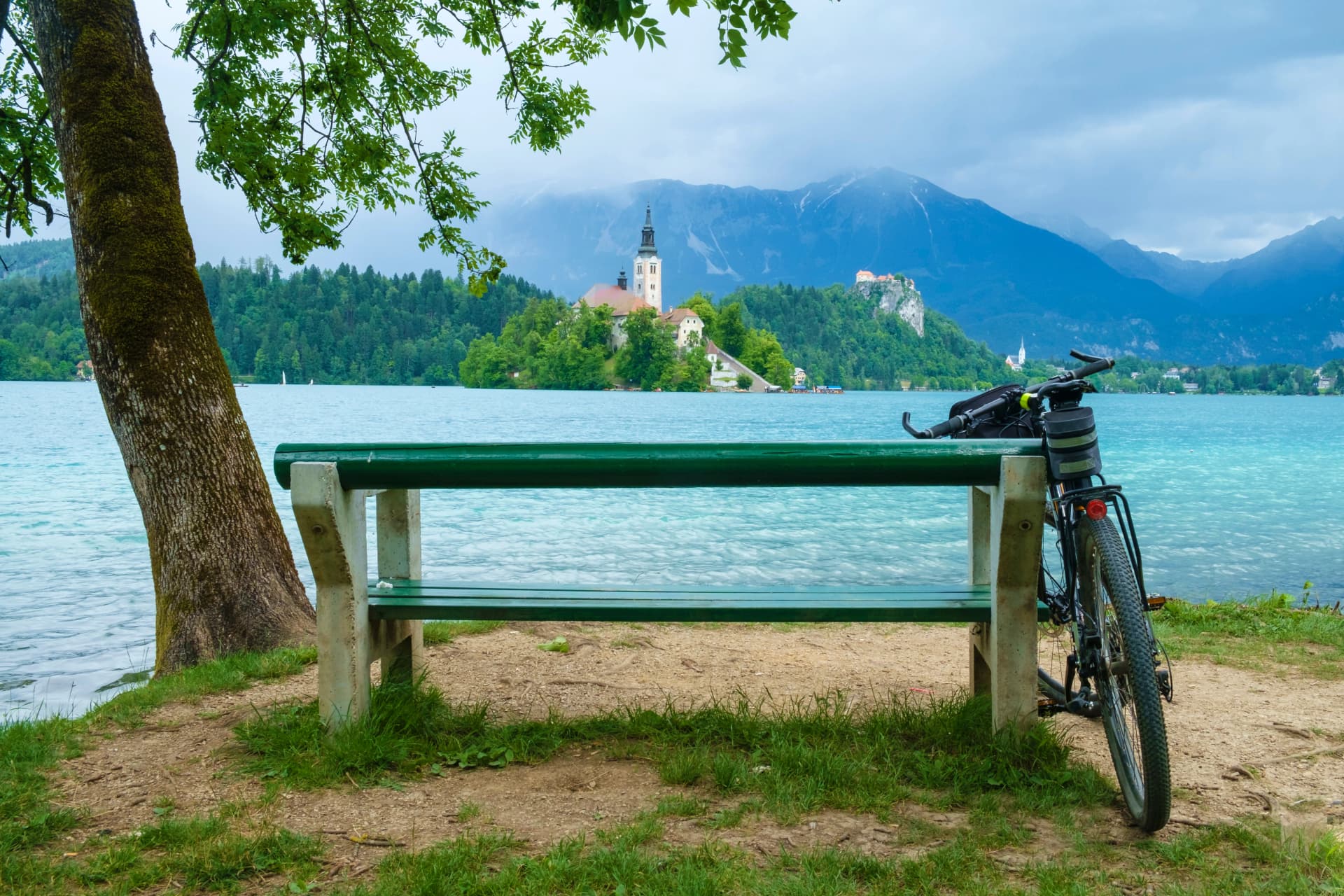 Bicycle leaning on the bench on the bank of Bled lake on a summer day.