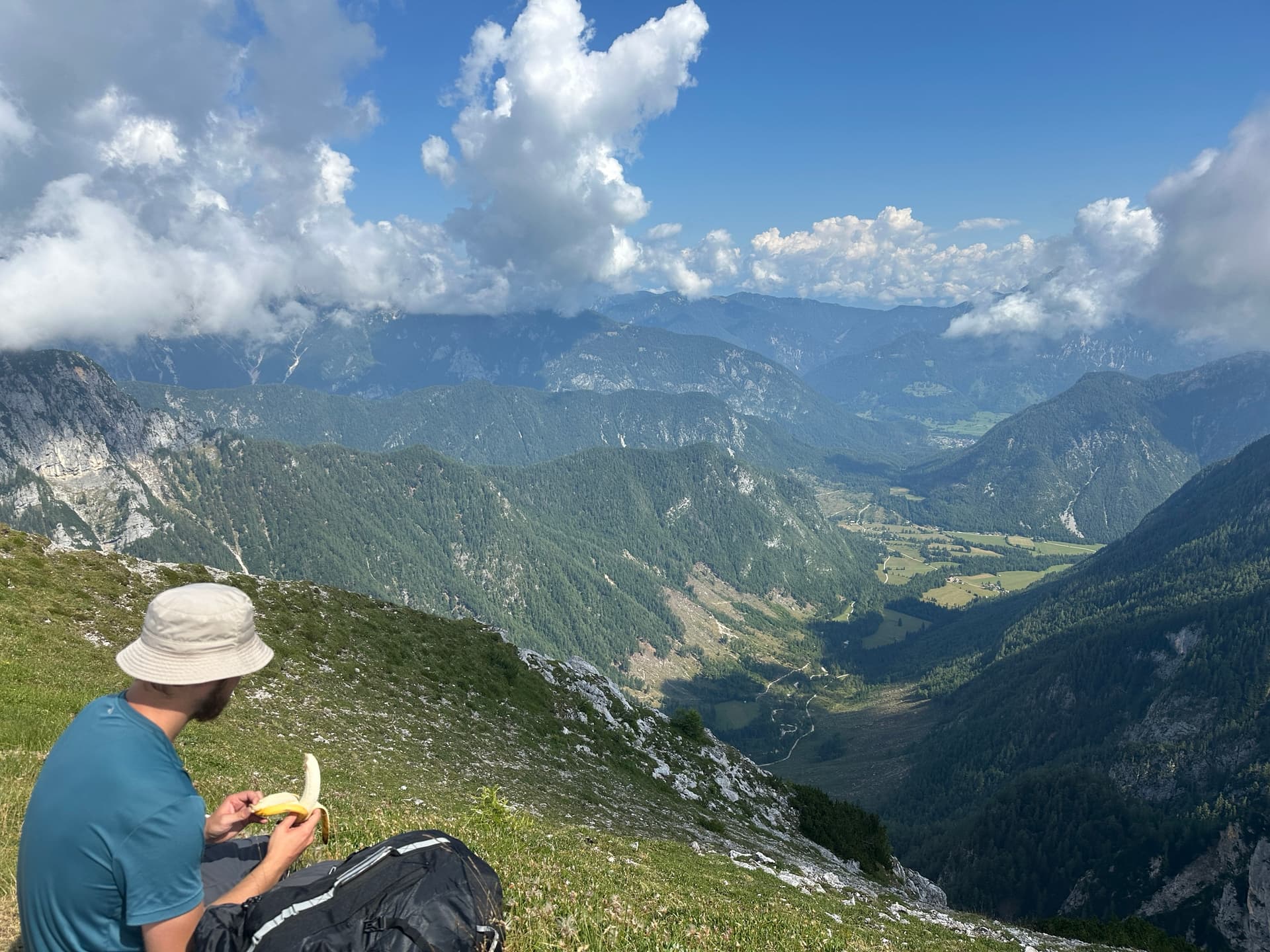 Hiker eating a banana on a mountain ridge overlooking a valley