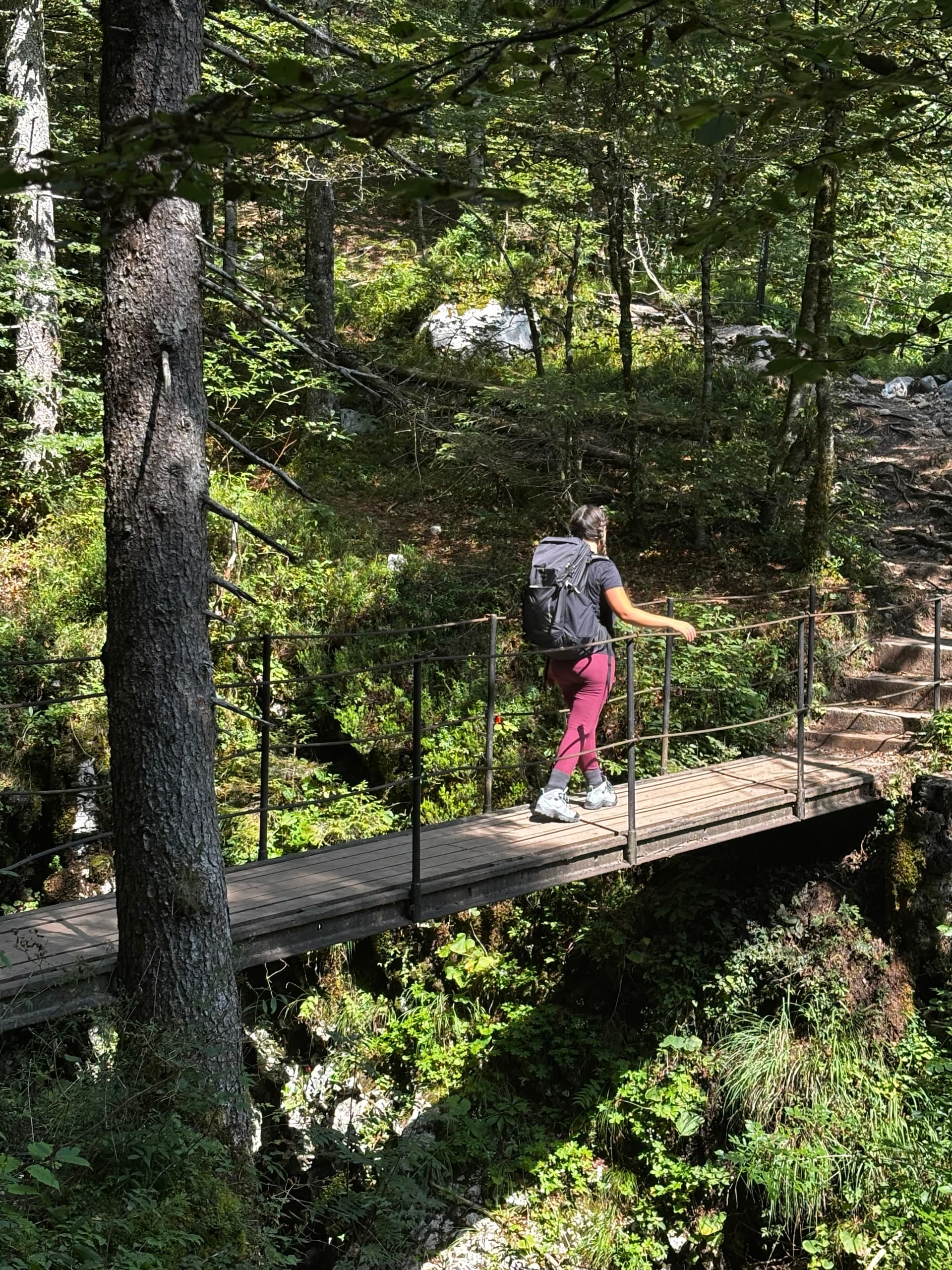 Hiker with backpack crossing a wooden footbridge in a forest