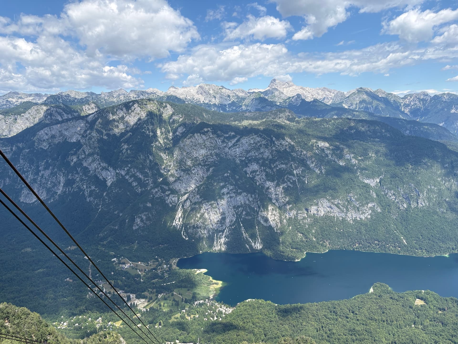 Lake Bohinj viewed from above with surrounding Julian Alps and cable car lines