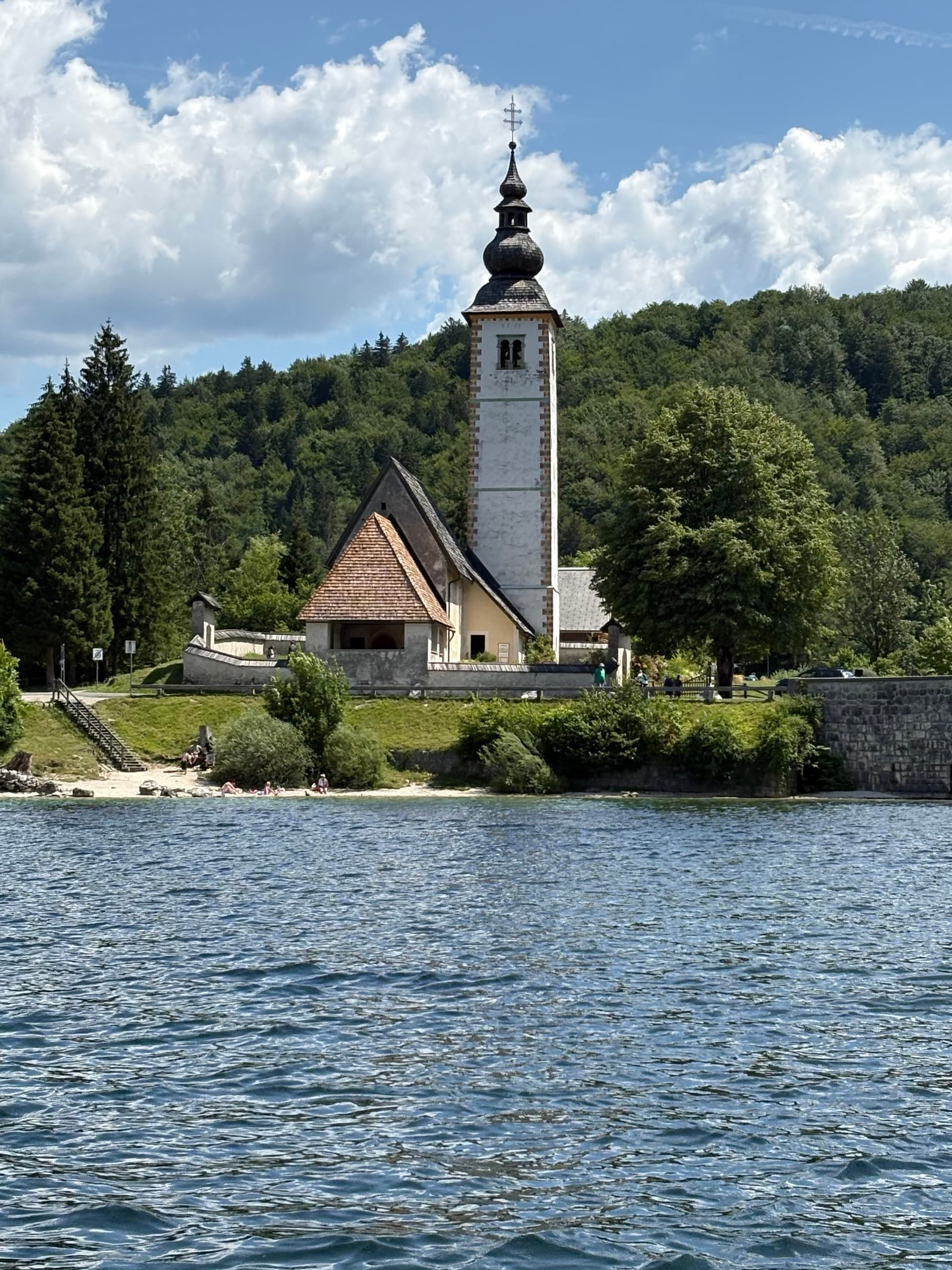 Church at Bohinj lakeside with steeple and forest backdrop