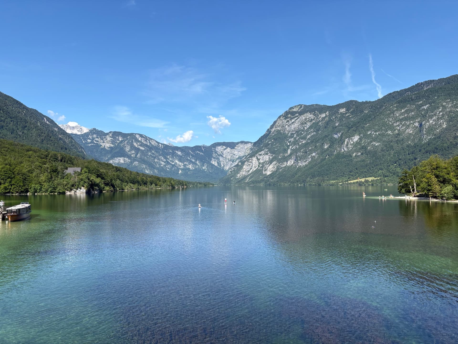 Lake Bohinj between wooded mountains and blue sky