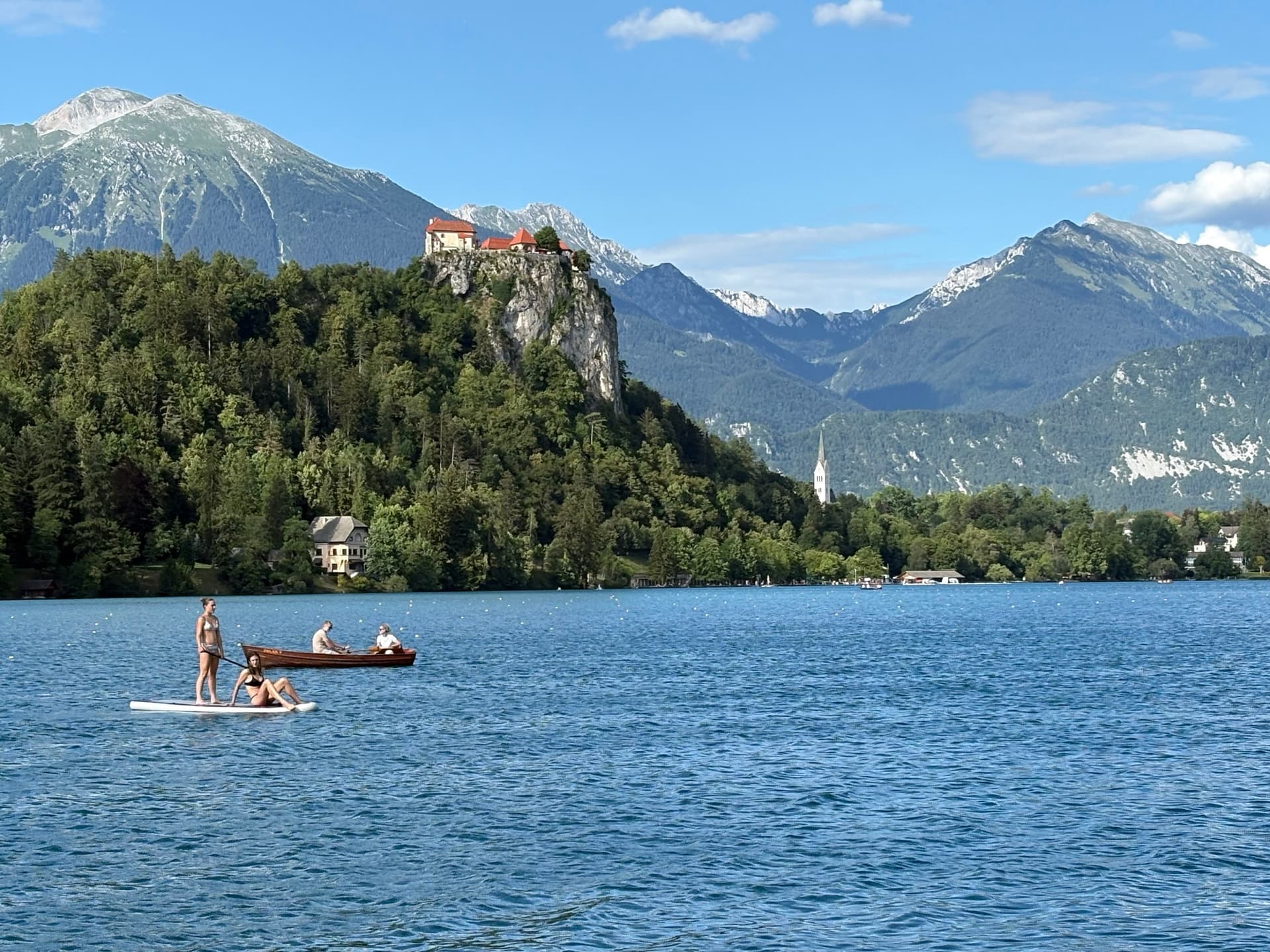 Paddleboarders on Lake Bled below Bled Castle with Julian Alps in Slovenia