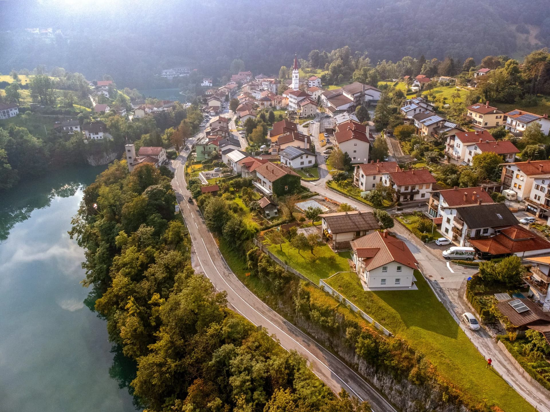 Aerial view of Most na Soči village with Soca river and steep forested hillsides