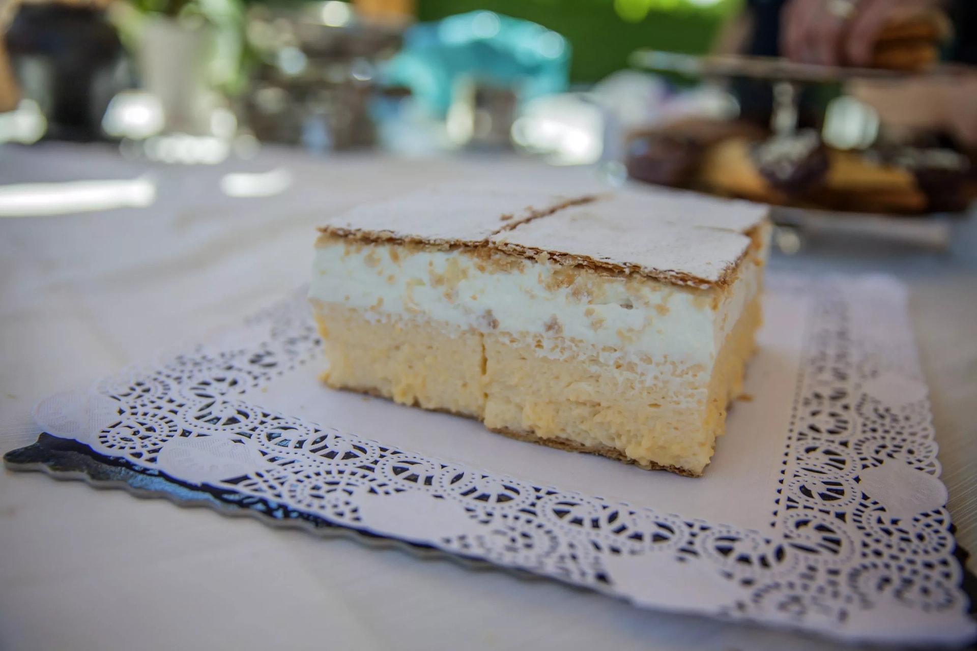 Kremna Rezina cream cake dusted with powdered sugar on a lace doily in Slovenia.